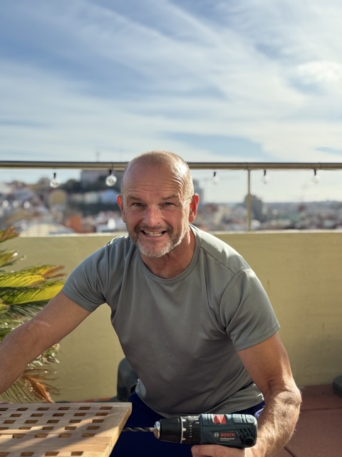 Marco Blom on a Lisbon terrace, holding a drill, with the city behind him